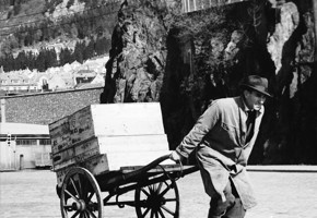 Black and white photo of a man moving fish boxes