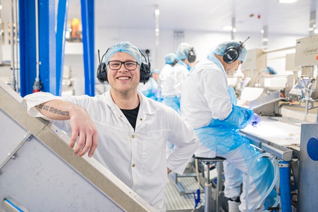 A man smiling with other men working behind him.