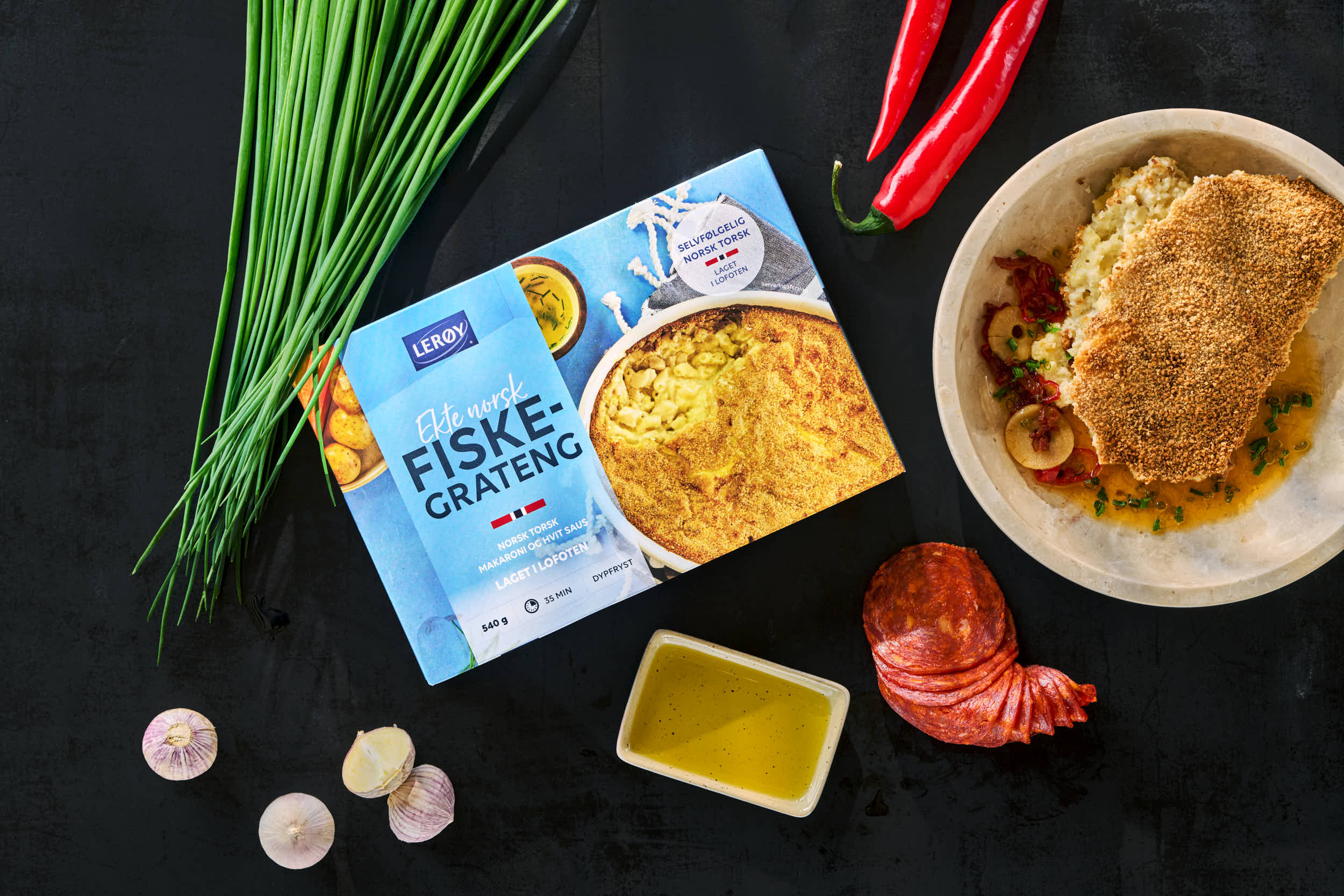 Mørk bakgrunn med et fat med fiskegrateng 