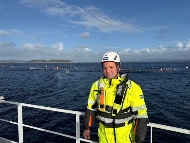 A man in bright yellow work-wear, behind him we see the ocean and skies. 