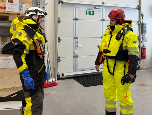 To kvinner i arbeidstøy snakker med hverandre